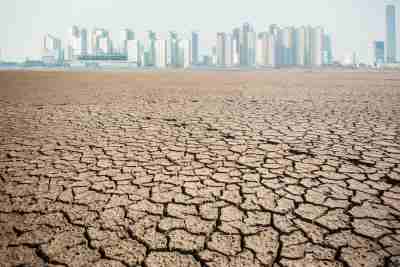 Drought cracked ground with city buildings in background